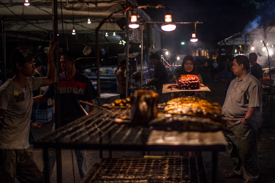 A man and woman contemplate grilled meat in Brunei.